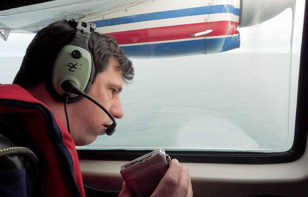 Daniël Beuker telt vanuit het vliegtuig en spreekt de waarnemingen in op een dictafoon, Noordzee, 3 november 2017.