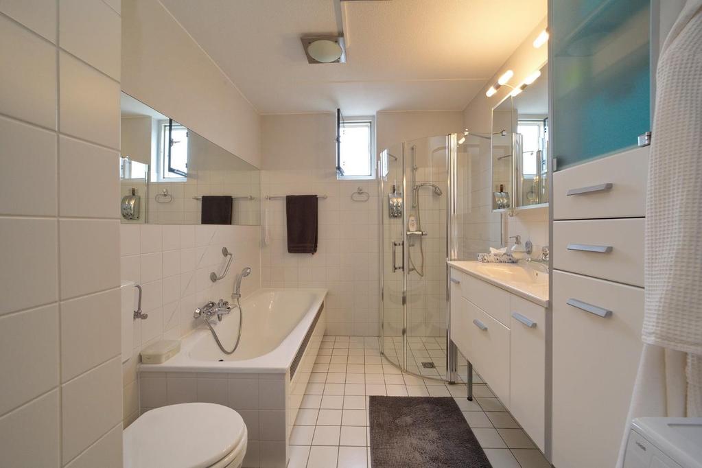 Badkamer (1 e verdieping) De gedeeltelijk betegelde badkamer beschikt over een douche,