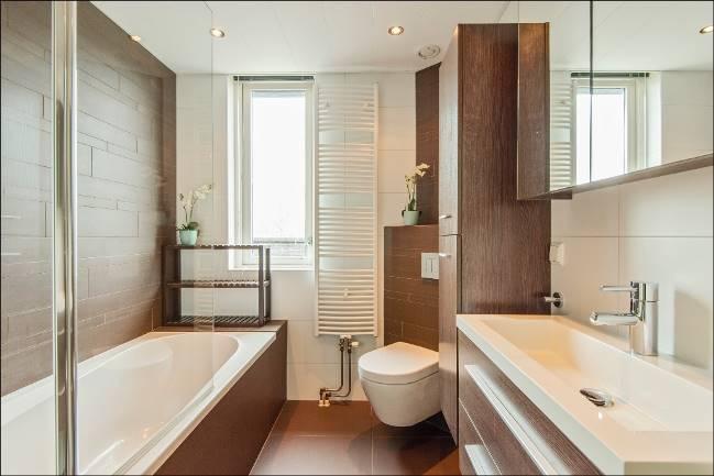 De luxueuze badkamer heeft een moderne betegeling en is van alle gemakken voorzien. Het royale ligbad is uitgevoerd met een glazen scherm, zodat u spatvrij in dit bad kunt douchen.