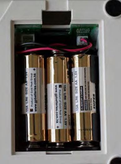 De batterijgreep met de ingezette batterijen in de display zetten. Opletten dat de leiding niet gedrukt wordt. Het deksel van de batterijcontainer sluiten.