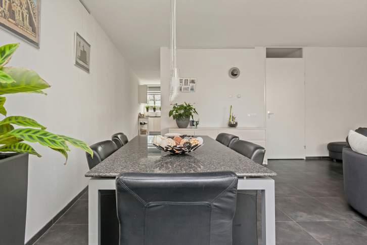 KEUKEN De moderne, half open keuken is greeploos uitgevoerd in wit met een donkerkleurig granieten aanrechtblad.