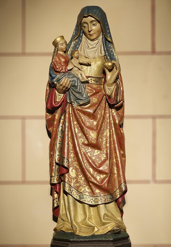Moeder Anna staat en draagt Maria op haar rechterhand. In haar linkerhand houdt ze tussen duim en wijsvinger een appel, waarnaar het kindje op Maria s schoot zijn handjes uitstrekt.