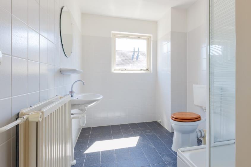 De badkamer: De nette badkamer bevindt zich aan de voorzijde van de woning en is uitgevoerd met een grijze vloertegel en wanden welke in neutrale kleurstelling zijn betegeld.