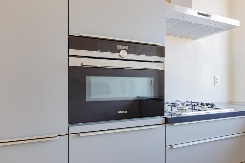 De keuken is geplaatst in een praktische L-opstelling en uitgevoerd in een antracietgrijze