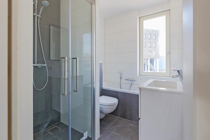 De badkamer: De moderne badkamer is ruim van afmeting en volledig betegeld in antracietgrijze/witte