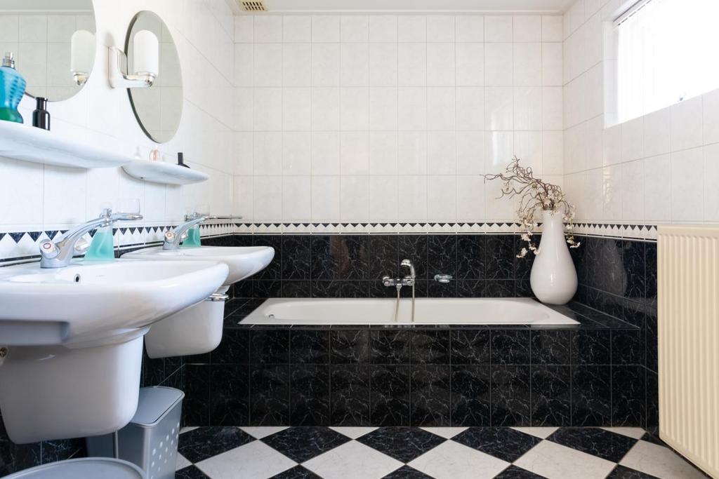 De eerste badkamer is geheel betegeld en uitgevoerd in een moderne zwart/wit kleurstelling.