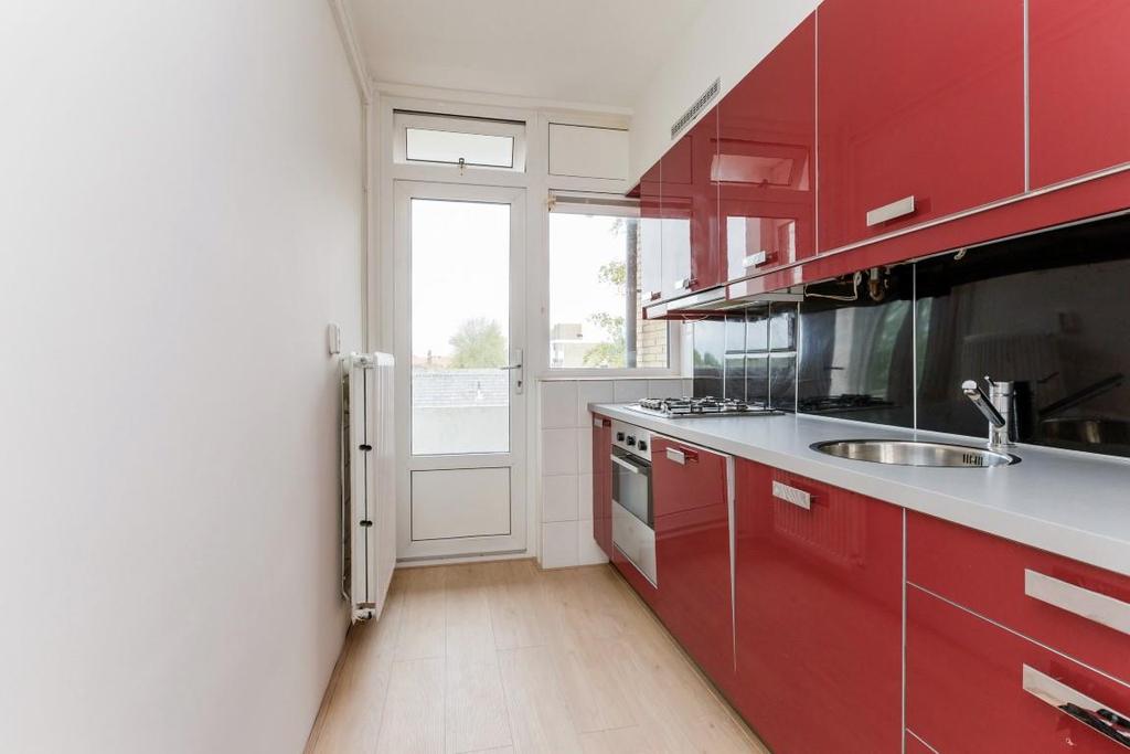 De keuken: De keuken is uitgevoerd met moderne rode fronten en een licht