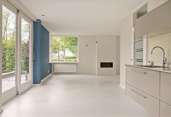 Als u verder loopt door de woning komt u in de ruime lichte woonkamer voorzien van een gashaard en een open moderne keuken met inbouwapparatuur.