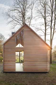 Aan de dichte, lange zijde van het huis zijn alle voorzieningen slim geïntegreerd in een wand van eikenhout: de keuken, een houtkachel, alle