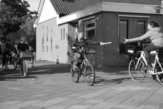 in een groep, lopen langs een obstakel op de stoep. Lessen groep 3 en 4: Starten, stoppen en kijken ; de leerlingen fietsen een route waarbij ze stoppen bij het stopbord en links-rechtslinks kijken.