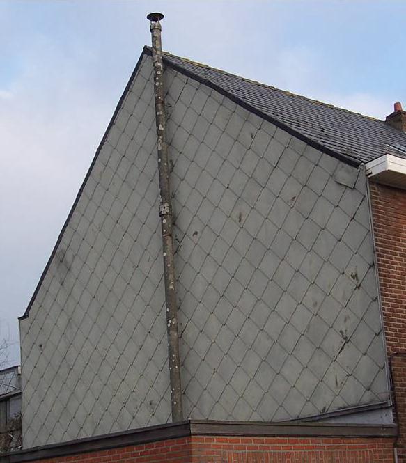 Zwarte leistenen in asbestcement op de puntgevel van een woning en schoorstenen in asbestcement Dak, gevel en schouw in