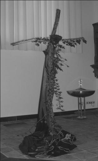 Uitleg bij de liturgische bloemschikking in de lijdenstijd In de schikking staat het kruis centraal. Het kruis is gemaakt van ruwe boomstammetjes, een verwijzing naar de Levensboom.