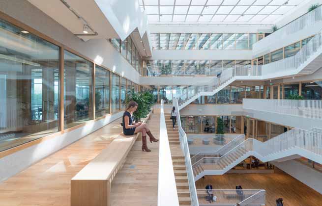 Polak gebouw Erasmus Universiteit Rotterdam Banken met planten aan het atrium. Zelfstudieruimte met maatwerkmeubilair in de binnenste schil.