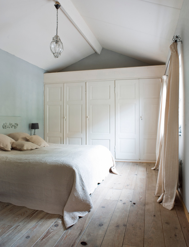 Foto linkerpagina: de kast in de slaapkamer bestaat uit oude sloopdeuren. De houten vloer heeft een verouderd effect gekregen dankzij de witte olie en dankzij de aanwezige gaten die zijn gebleven.