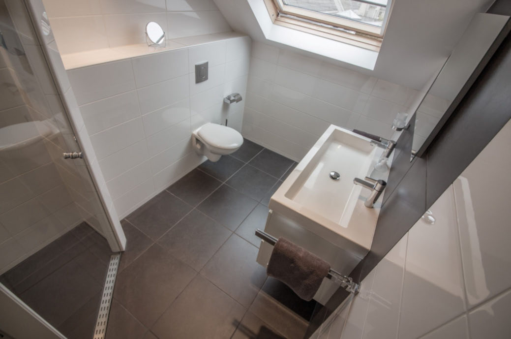 De moderne badkamer is voorzien van een wastafelmeubel met dubbele kraan,