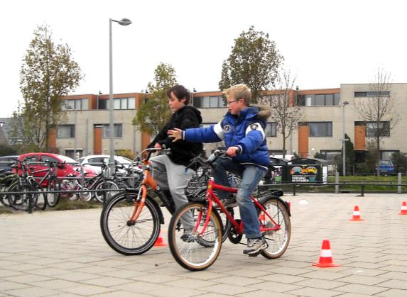 schoolplein Fietsen is tevens bewegen, meester Fabian organiseert en geeft met de leraren verkeersles. Ouders helpen.