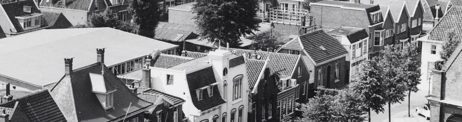 Foto uit 1960 met het houten huis in de rooilijn van de oostelijke belendingen ter linker zijde.