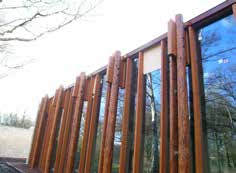 Door de houten constructie en de combinatie met de transparante glasgevel lijkt het gebouw over te gaan in het park en andersom.