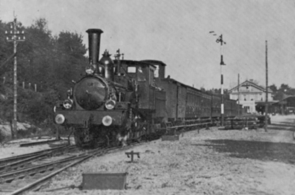 Afb. 7: Een HSM-trein in de bocht bij Baarn, richting Hilversum, aangespannen met Borsig locomotief 187 uit ca. 1888. Op de achtergrond het fraaie koninklijke station van de HSM.