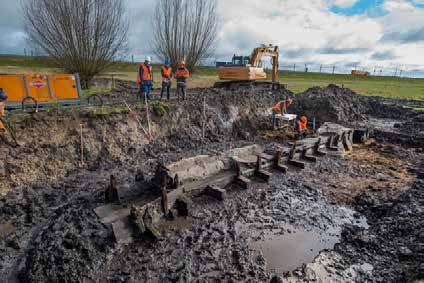 Afb. 39b28. Bijzondere archeologische vondst van een steigerconstructie ter hoogte van De Enk [foto: Isala Delta]. Afb. 39b30. Impressie van de opgraving van vindplaats 9 [foto: ADC].