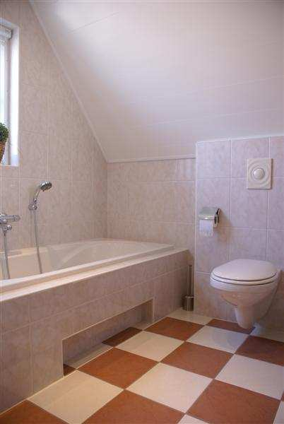 Fraaie geheel betegelde badkamer in lichte kleurstelling en het volgende sanitair: - wastafel - royaal ligbad - hangcloset - designradiator -