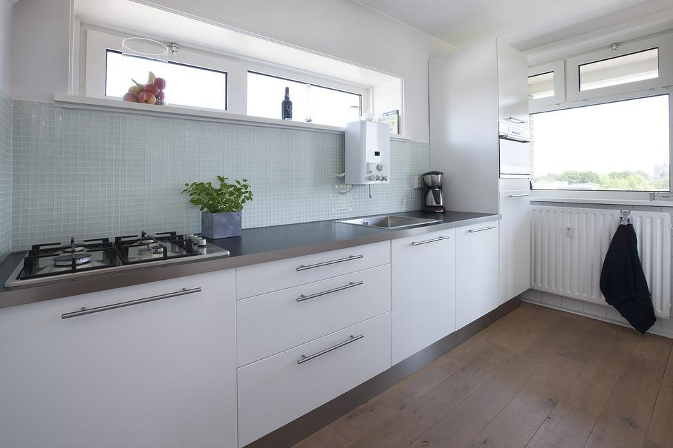 INDELING Keuken, is voorzien van dezelfde eiken vloer, glasmozaïek achterwand en stucwerk plafondafwerking.