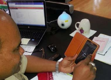 Districtscommissaris Nerkust van Paramaribo Z-W bekijkt ingekomen stukken van zijn commissariaat op zijn mobiel.