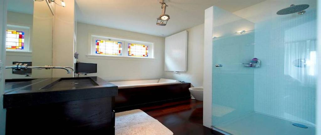 Badkamer Zeer luxe, eigentijdse badkamer met fraaie hardhouten vloer en glas-in-loodramen.