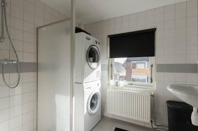 De badkamer is geheel betegeld in een grijs/witte kleurstelling. De sanitaire uitrusting bestaat uit een douchegelegenheid met thermostaatkraan en een wastafel.