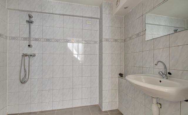 De badkamer heeft een wandcloset, wastafel met meubel, ligbad met douche en is 100 % betegeld.