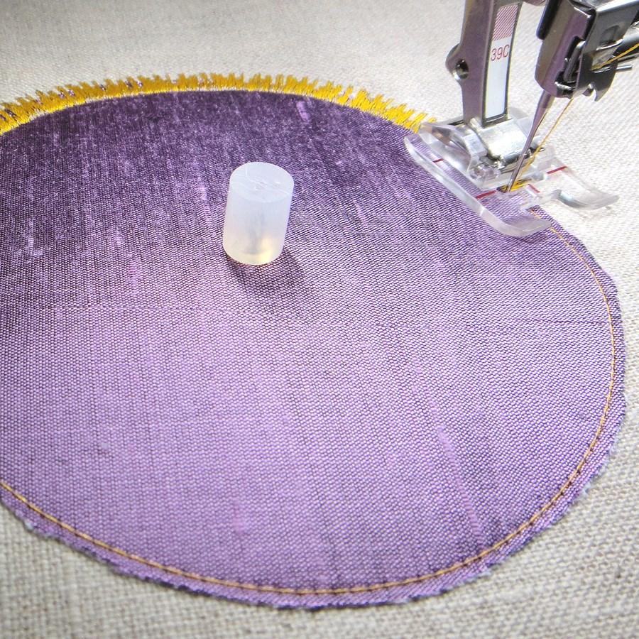 Cirkel-applicatie Creëer cirkel-applicaties door de twee-stappen-methode. Naai eerst een cirkel in rechte steken op een lapje stof, naai dit op achtergrondstof, knip de overtollige stof af.