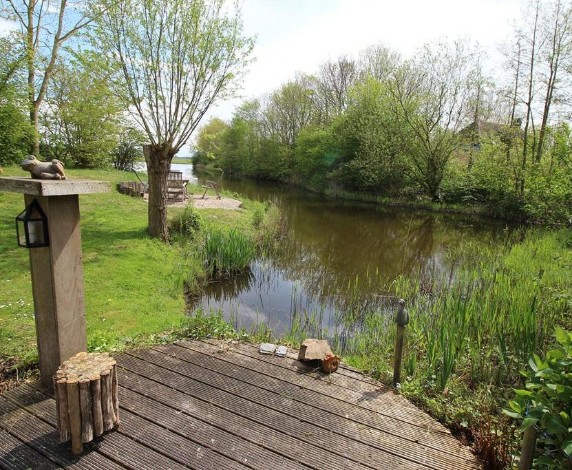 Begane grond: u-vormige living met vijf openslaande dubbele deuren en extra terras aan eigen water.