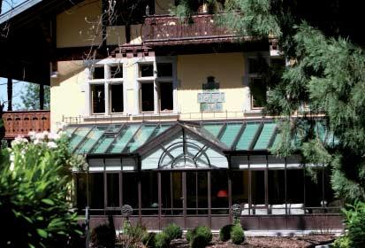 Deze roestkleurige veranda in oranjeriestijl staat in Zwitserland en past heel goed bij de typische chaletstijl van
