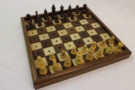 Speelbord met 64 in het midden geperforeerde vakken wat het plaatsen van de speelstukken vereenvoudigt, één vak op twee is in