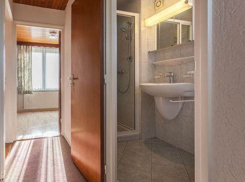 De badkamer is voorzien van toilet, wastafel, designradiator, douche met