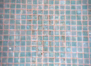 Lijmrillen zijn bij doorschijnende glastegels in voeggebied zichtbaar. Ongelijk mozaïekoppervlak en onrustig voegbeeld. Bruine (natte) vlekken onder het mozaïek bij continue waterbelasting.