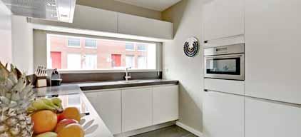 Vanuit de hal is de woonkamer bereikbaar, met aan de voorzijde een uitgebreide luxe strak uitgevoerde keuken met een vastkastenwand met combi oven en