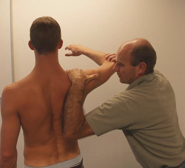 SRT: Scapular Reposition test : Therapeut stabiliseert Scapula met 1 arm: hand om acromion, palm t.h.v.