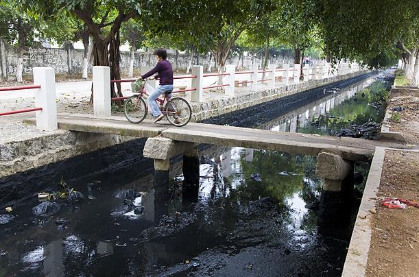 Figuur 3.3. Rivier door Guiyu, China. Het water ziet zwart door as van steenkool die na het stoken in de rivier gedumpt wordt. Het water bevat ook veel zware metalen die lekken uit het AEEA.