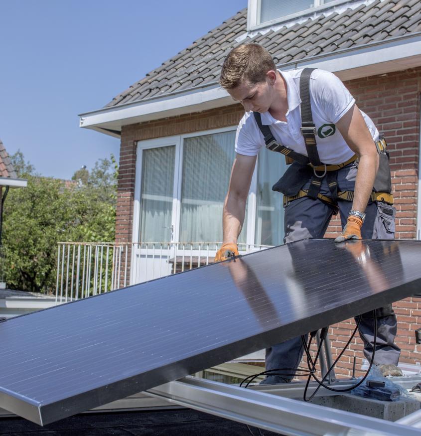 Een installateur bij u uit de buurt plaatst de zonne- panelen op uw dak.