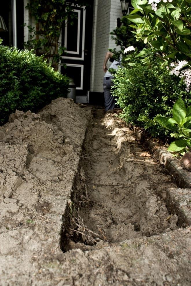 Als de sleuf naar de woning toe gegraven is, kan de nieuwe aansluitleiding in de sleuf worden