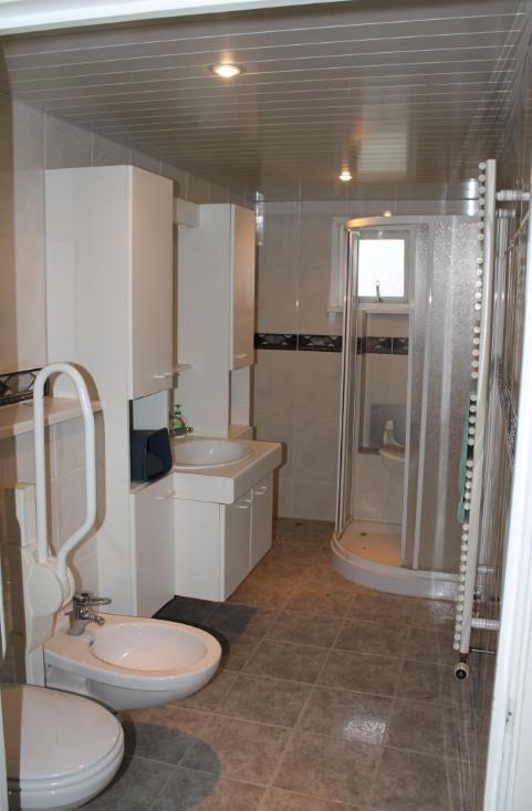 De badkamer, bereikbaar via de bijkeuken, geeft toegang tot de trapopgang naar de eerste