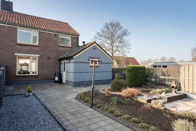 Achter het huis ligt een keurig onderhouden siertuin met diverse beplanting, siergrind en twee terrassen. Er is een metselwerk erfafscheiding met de buren.