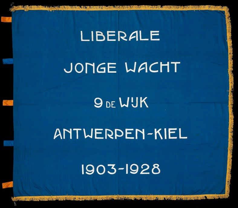 Nr. 62 Liberale Jonge Wacht, 9e Wijk Antwerpen 1928 katoen, lussen in zijde borduurwerk blauw/wit, gele franjes 131 x 150 cm lussen aan de