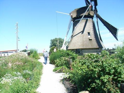 De Anke Maria langszij met de De tjalk van Rolf en Lia waar De watermolen de Rietvink, ondergaande zon op de horizon ze op wonen naast de molen staande aan de Helomavaart de Rietvink