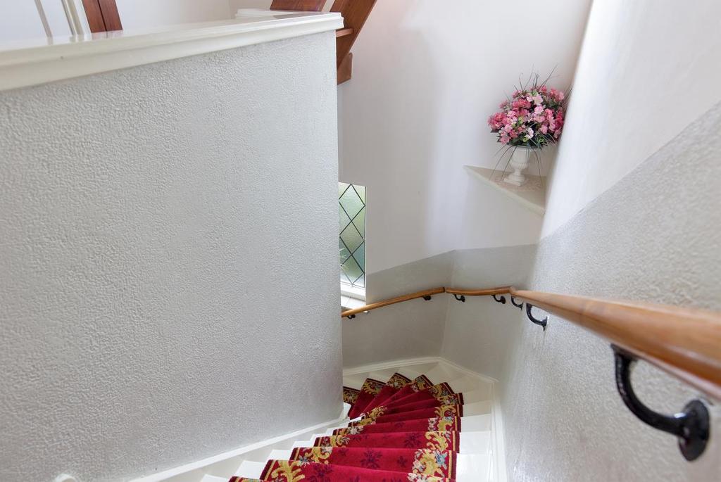 De wit geschilderde houten trap met bordes is voorzien van een loper.