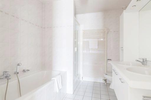 Grenzend aan deze slaapkamer is de grote betegelde badkamer gesitueerd voorzien van een badmeubel met dubbele