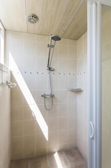 De eenvoudige badkamer is voorzien van een wastafel en een douchecabine.