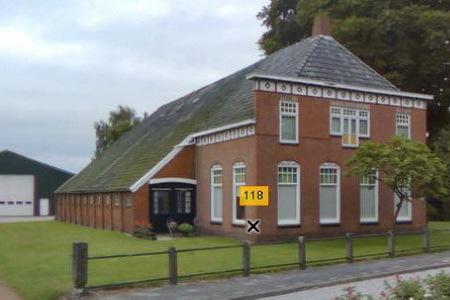 Oldambtster boerderij met bijzondere voorgevel in neoclassicistische trant, voorzien van lijstgoot en pilasters.