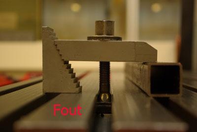 Kleinere machineklemmen worden op een geleiderail geschoven zodat de boor makkelijk boven het afgetekende punt kan worden.